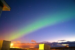 Cielo nocturno con estrellas visibles y la aurora boreal.