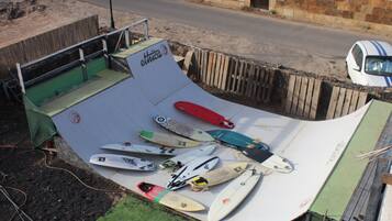 A skate ramp with various surfboards and a car parked nearby.