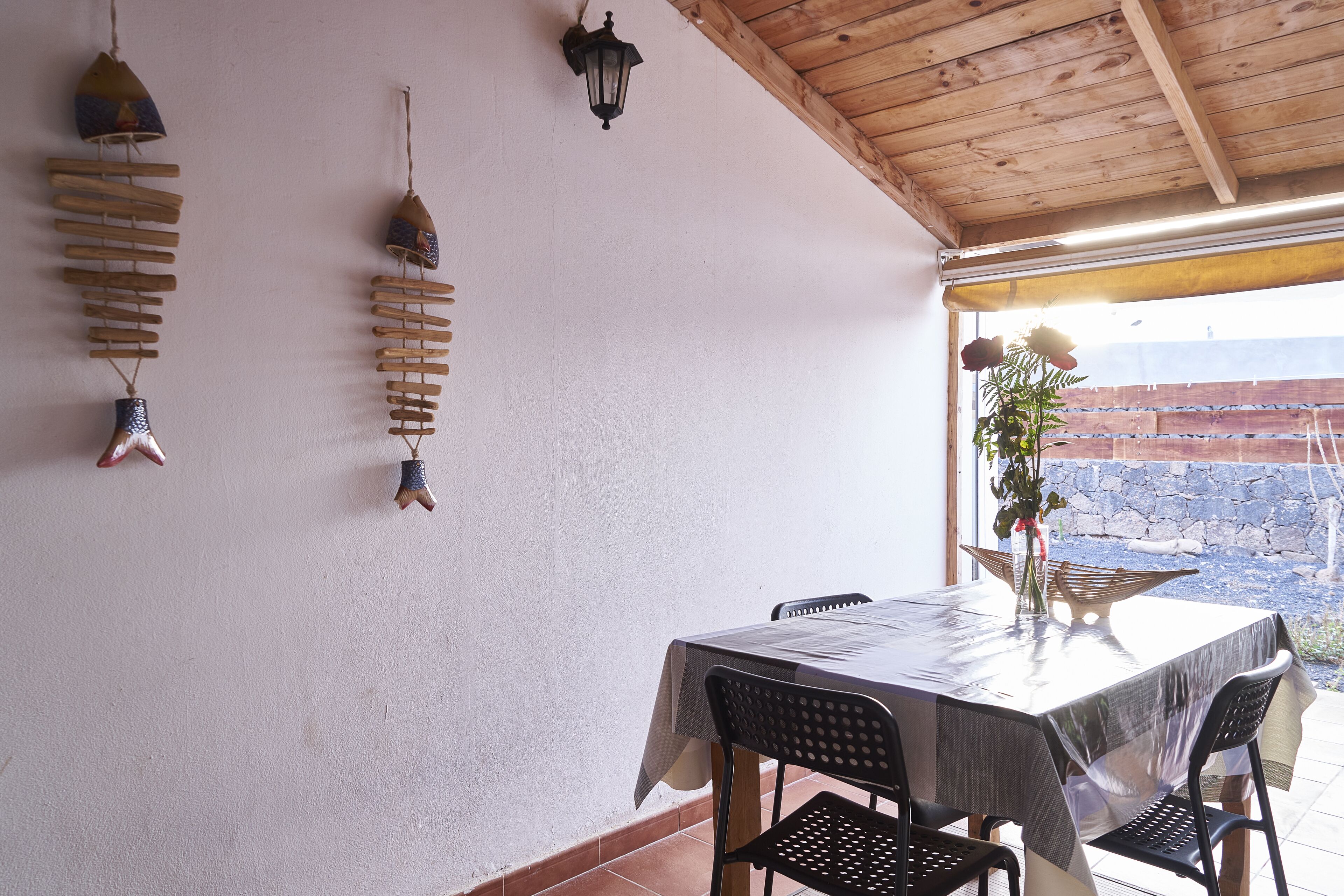Zona pranzo con tavolo apparecchiato per due, travi a vista in legno e oggetti decorativi appesi alle pareti.