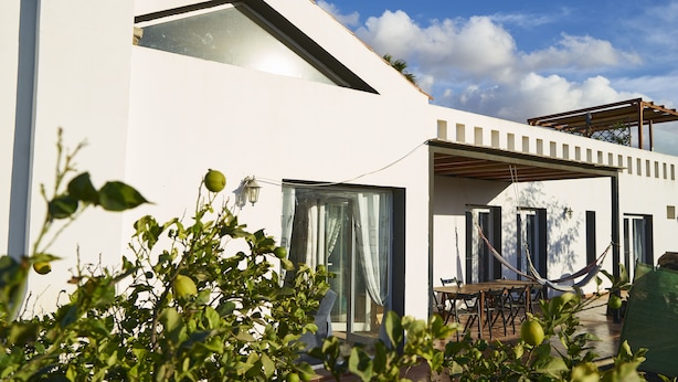A modern house with a large glass door, a hammock, and a patio area. - Da Mata Kite&Surf House (La Oliva)