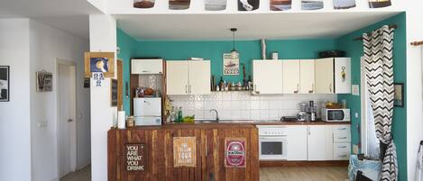 A kitchen with wooden cabinets, a central island, and a dining area with a patterned tablecloth.