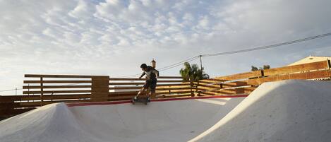 Un patinador en un parque de skate con rampas de madera y cielo despejado.