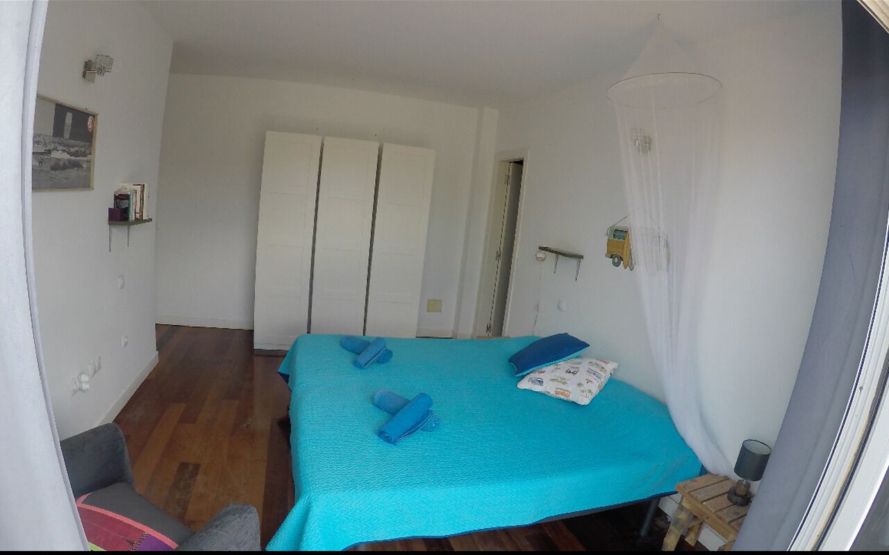 A room with a bed, a chair, a small table, and a door.