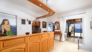 A kitchen with wooden cabinets, a large window, and a view of the ocean. - Seafront Aegeans blue pearl over infinity pool (Keratea)