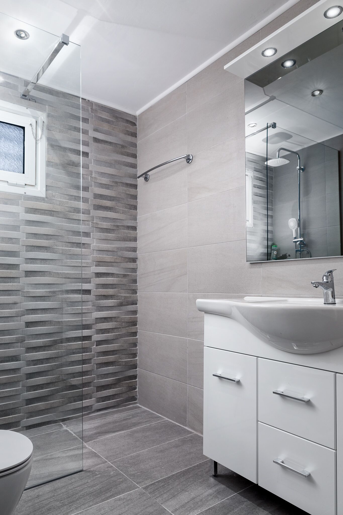 A modern bathroom with a shower, toilet, and vanity.