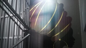 A staircase with a metal railing and a wall with a colorful abstract mural. - Haridge Inn (Nairobi)