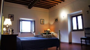 Une chambre à coucher avec un lit, une fenêtre, une chaise et une table avec une lampe.