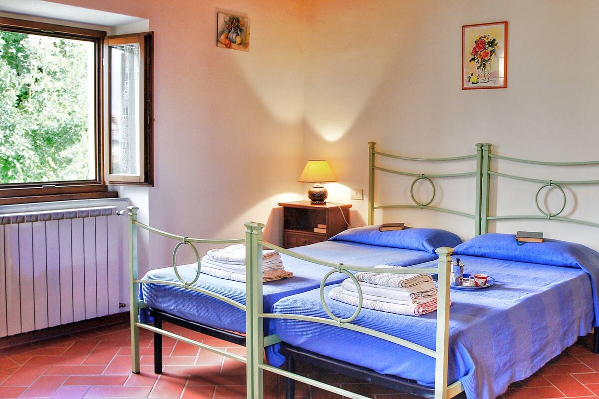 Une chambre avec deux lits, une fenêtre, un radiateur et une commode.