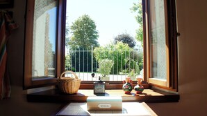 Ein Fenster mit Gartenblick, ein Korbwäschekorb, eine kleine Schachtel mit dem Aufdruck „TEE“ und zwei dekorative Vasen.