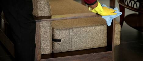 A person cleaning a wooden chair with a cushion.