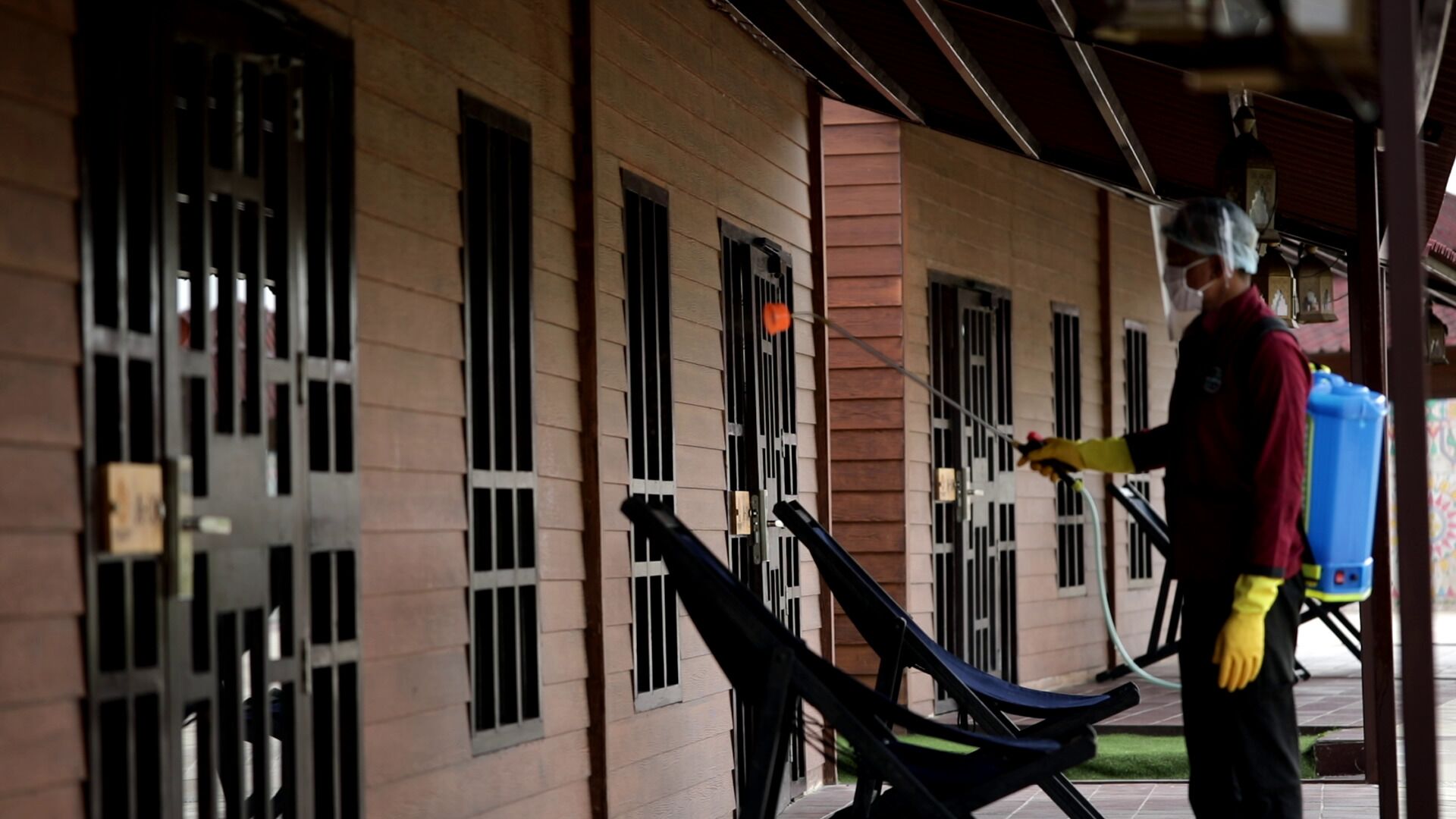 Una persona limpiando ventanas de un edificio con barandales y un espacio exterior cubierto.