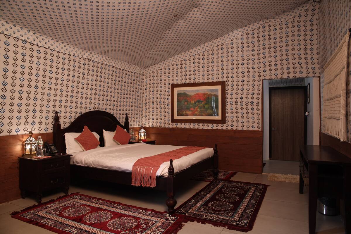 A bedroom with a wooden bed, a nightstand, a lamp, and a painting on the wall.