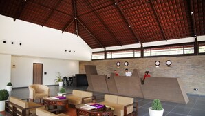 A spacious lobby with a high ceiling, seating areas, a reception desk, and a view of the outdoors. - Statue Of Unity Tent City (Garudeshwar)