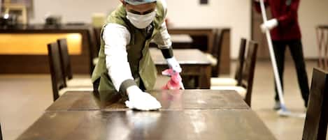 A person cleaning a table in a restaurant setting.