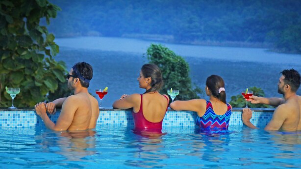 A poolside view with a view of the sea and trees in the background. - Statue Of Unity Tent City (Garudeshwar)