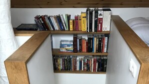 A small, enclosed reading nook with wooden bookshelves filled with books. - Skipholt (Vogar)