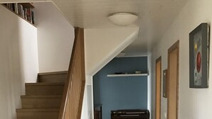 A wooden staircase leading to a landing with a blue wall and a shelf above it. - Skipholt (Vogar)
