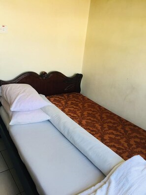 A single bed with a wooden headboard, a white pillow, and a brown patterned bedspread. - Sir James Hotel (Nairobi)