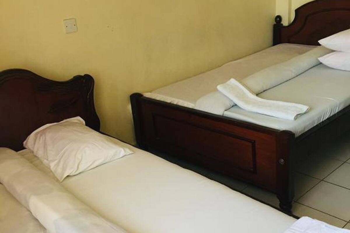 Une chambre avec deux lits simples, chacun doté d’une tête de lit en bois et de linge de lit blanc.