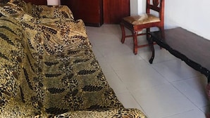 Um quarto com um sofá de pelo de leopardo, um armário de madeira, uma cadeira de madeira e um banco.