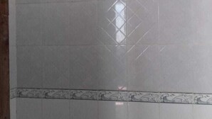 Área de chuveiro com azulejos e chuveiro manual.