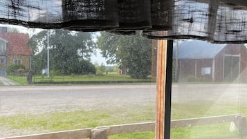 Una finestra con vista su una zona erbosa e una strada.