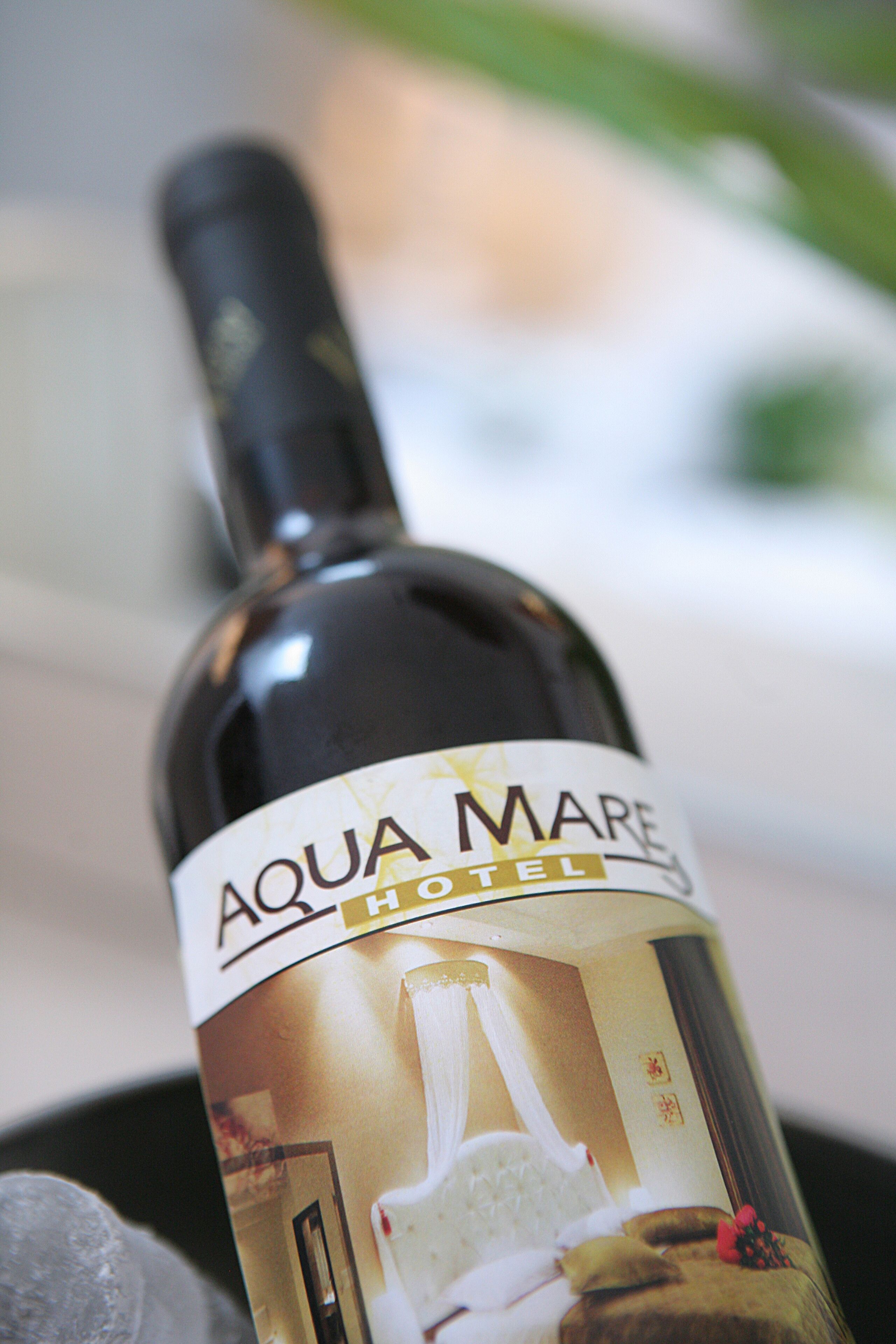 Una bottiglia di vino dell'hotel Aqua Mare con etichetta raffigurante un letto e fiori.