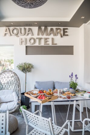 A dining area at the Aqua Mare Hotel with a buffet table, seating, and a wall sign. - Aqua Mare Hotel (Nea Propontida)