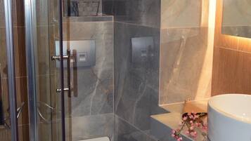 Un baño moderno con cabina de ducha de vidrio, inodoro y lavabo.