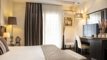 Una habitación de hotel con cama, escritorio, silla, televisión y lámpara.