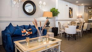 Una sala de estar moderna con un sofá azul, una mesa de centro de vidrio y un comedor con sillas blancas y una mesa.