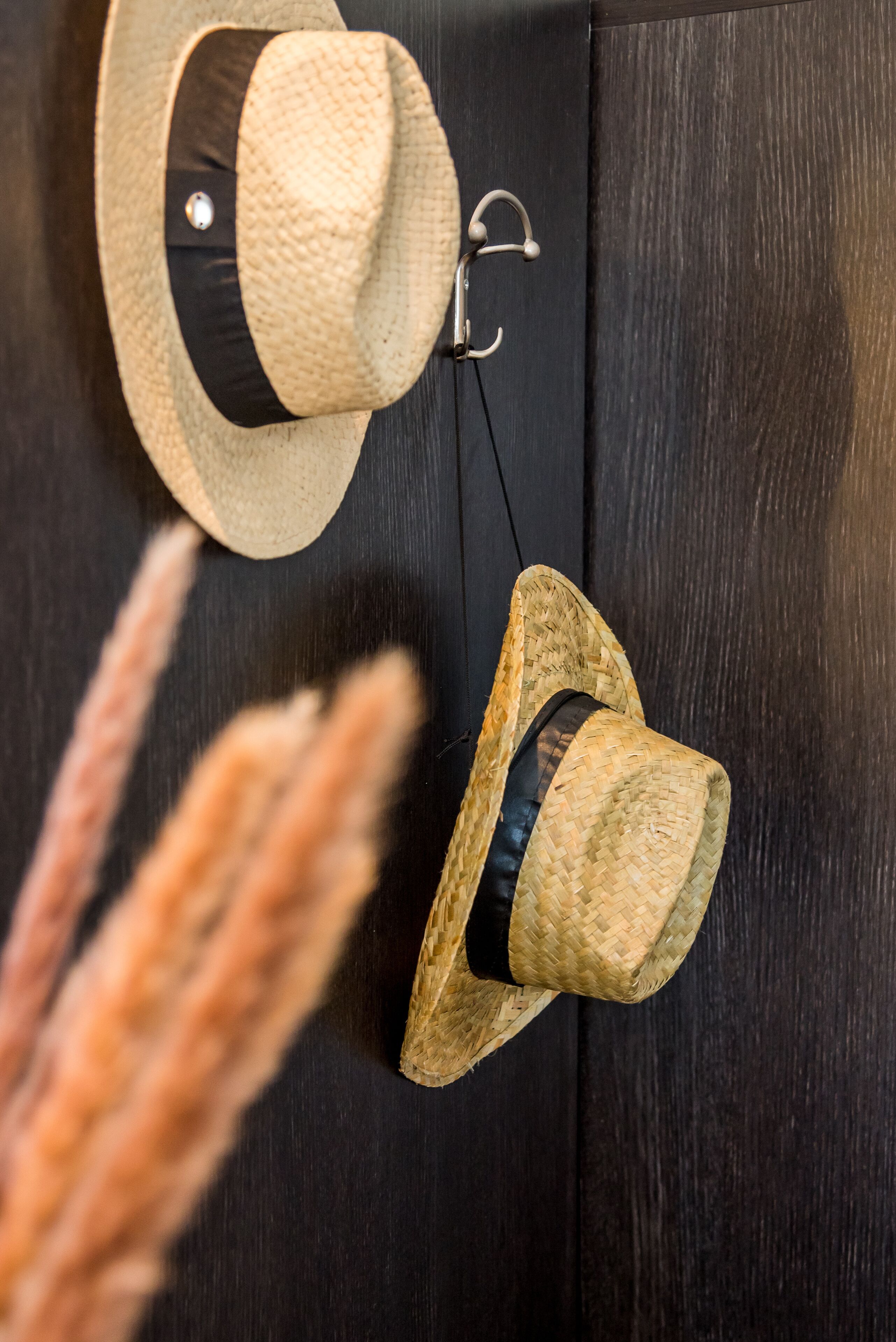 Two straw hats hanging on a dark wooden door.