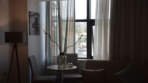 A modern living room with a sofa, a dining table with chairs, and a floor lamp. - Aqua Mare Sea Side (Nea Propontida)