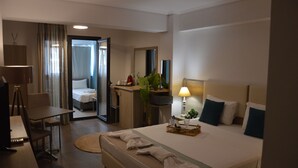 A hotel room with a bed, a desk, a chair, a lamp, and a bathroom visible through an open door. - Aqua Mare Sea Side (Nea Propontida)