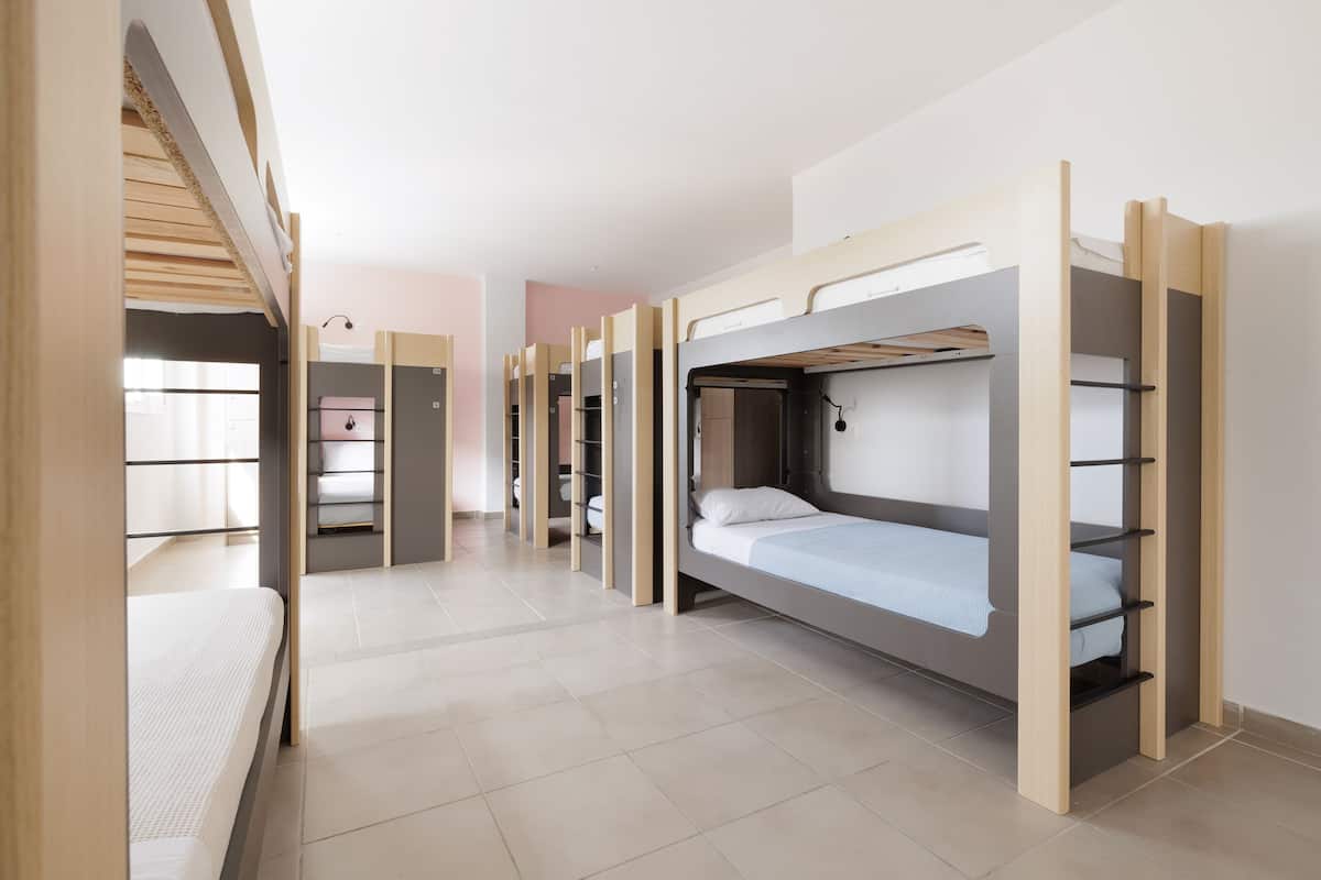 Un dormitorio con literas, un pequeño espacio kitchenette y una ventana con persianas.