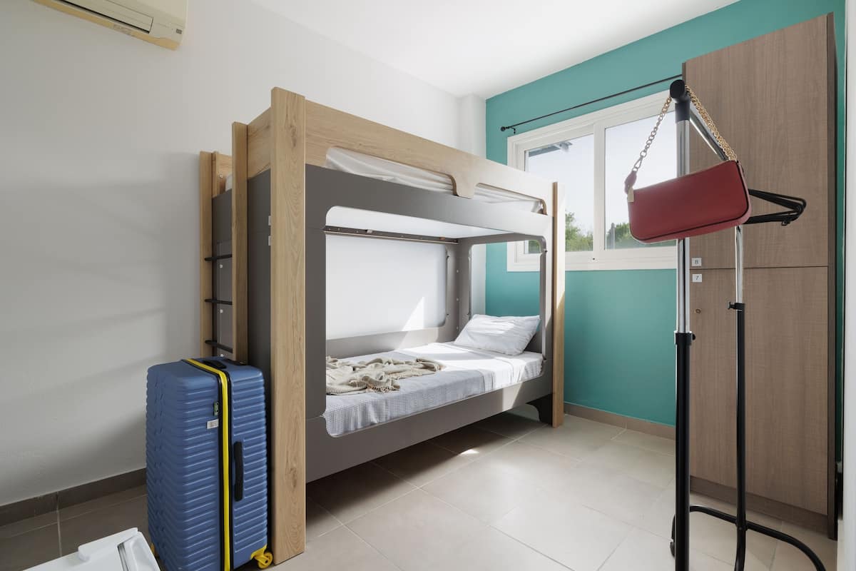 Habitación con literas, una maleta, una lámpara y un armario.