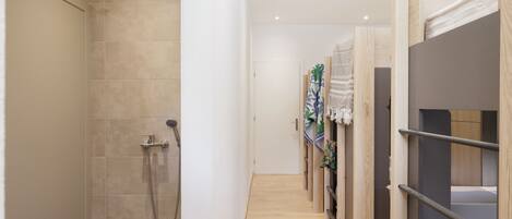 A hotel hallway with a shower, wooden bunk beds, and a tiled floor.
