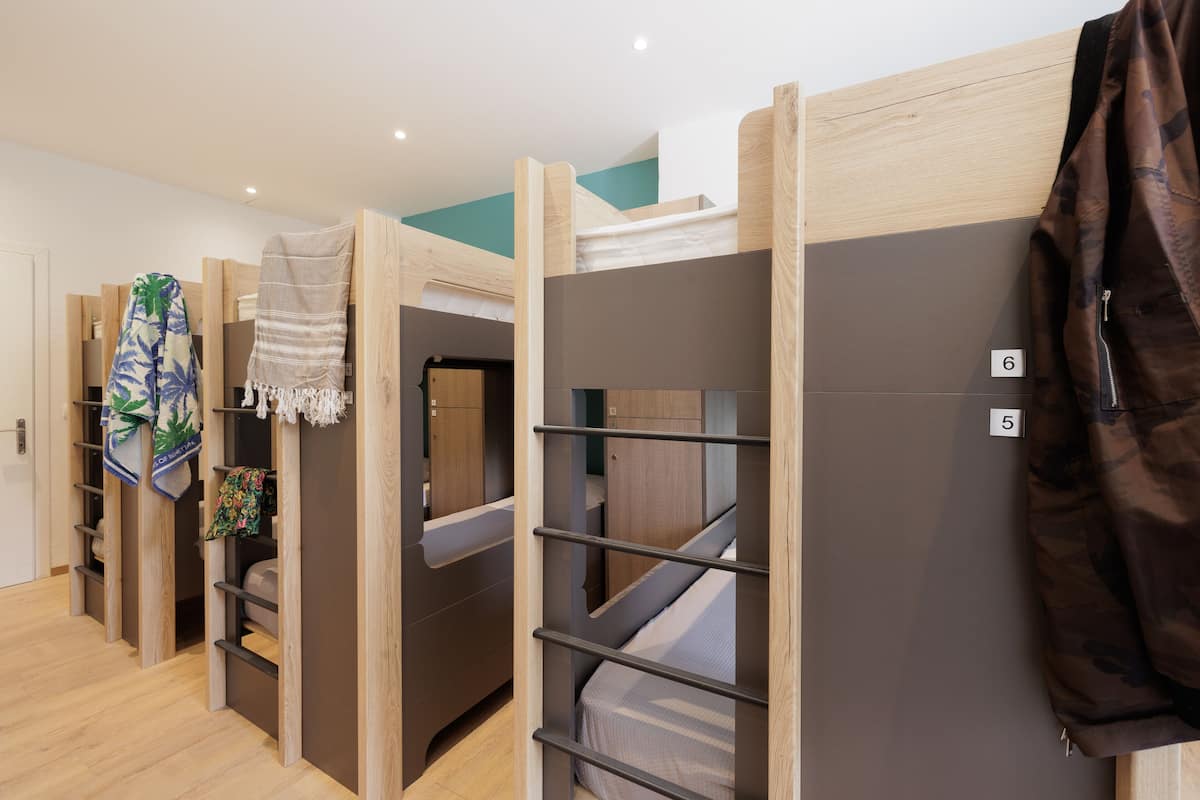 Un dormitorio con literas, muebles de madera y un perchero.