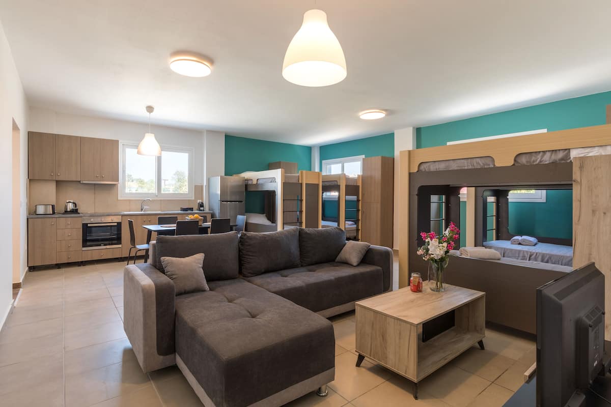 Un apartamento moderno con cocina, comedor y sala de estar con sofá y televisor.