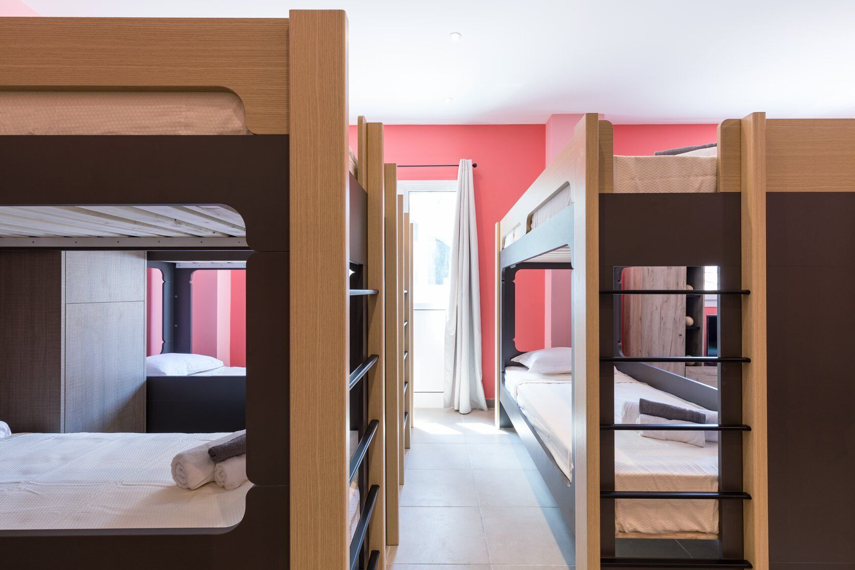 Un dormitorio con literas, un armario y una ventana con cortinas.