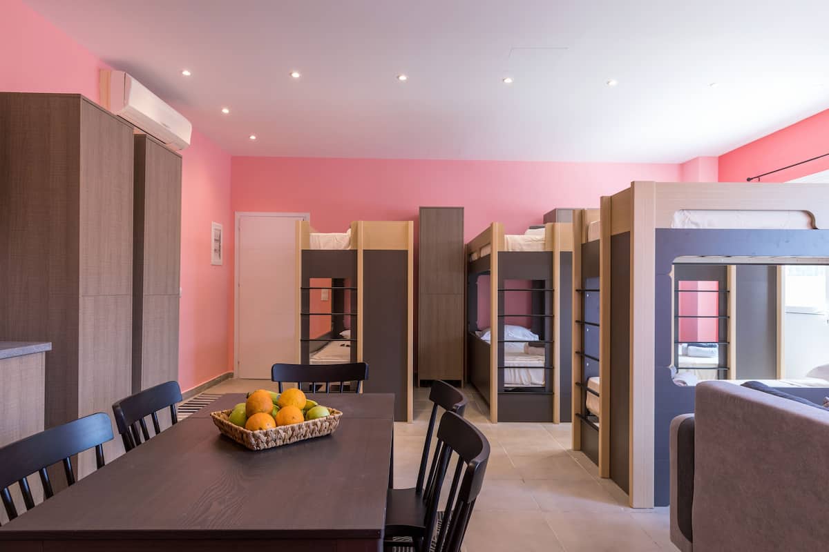 Una habitación de hotel moderna con literas, un comedor con fruteros y una kitchenette.
