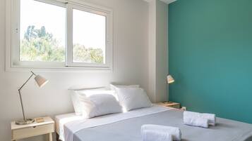 Un dormitorio con cama, dos mesitas de noche, una ventana y una pared de acento color verde azulado.