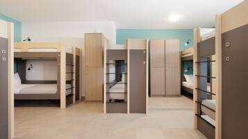 A dormitory room with bunk beds, wooden wardrobes, and a tiled floor.