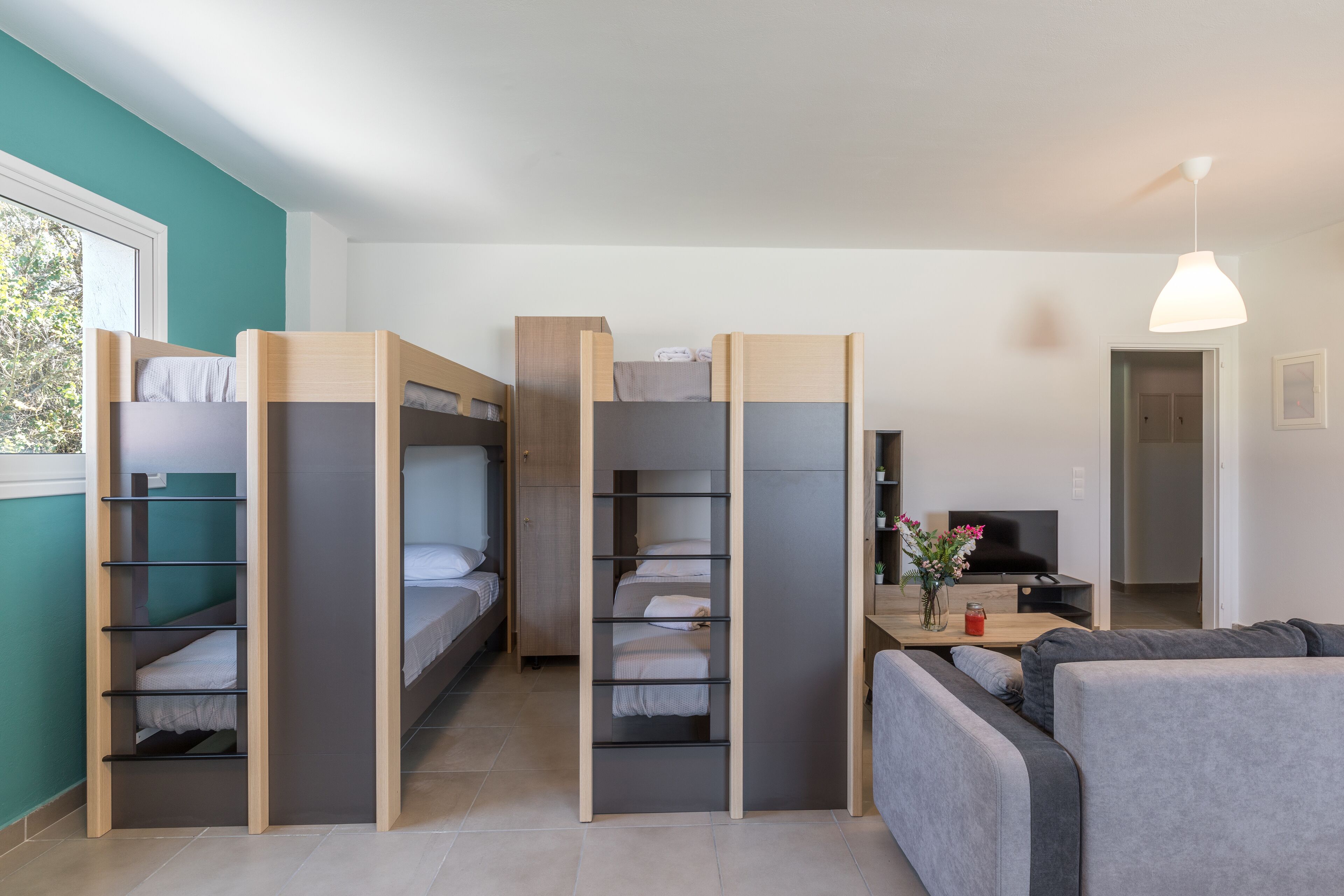 A compact room with bunk beds, a sofa, a desk, and a TV.