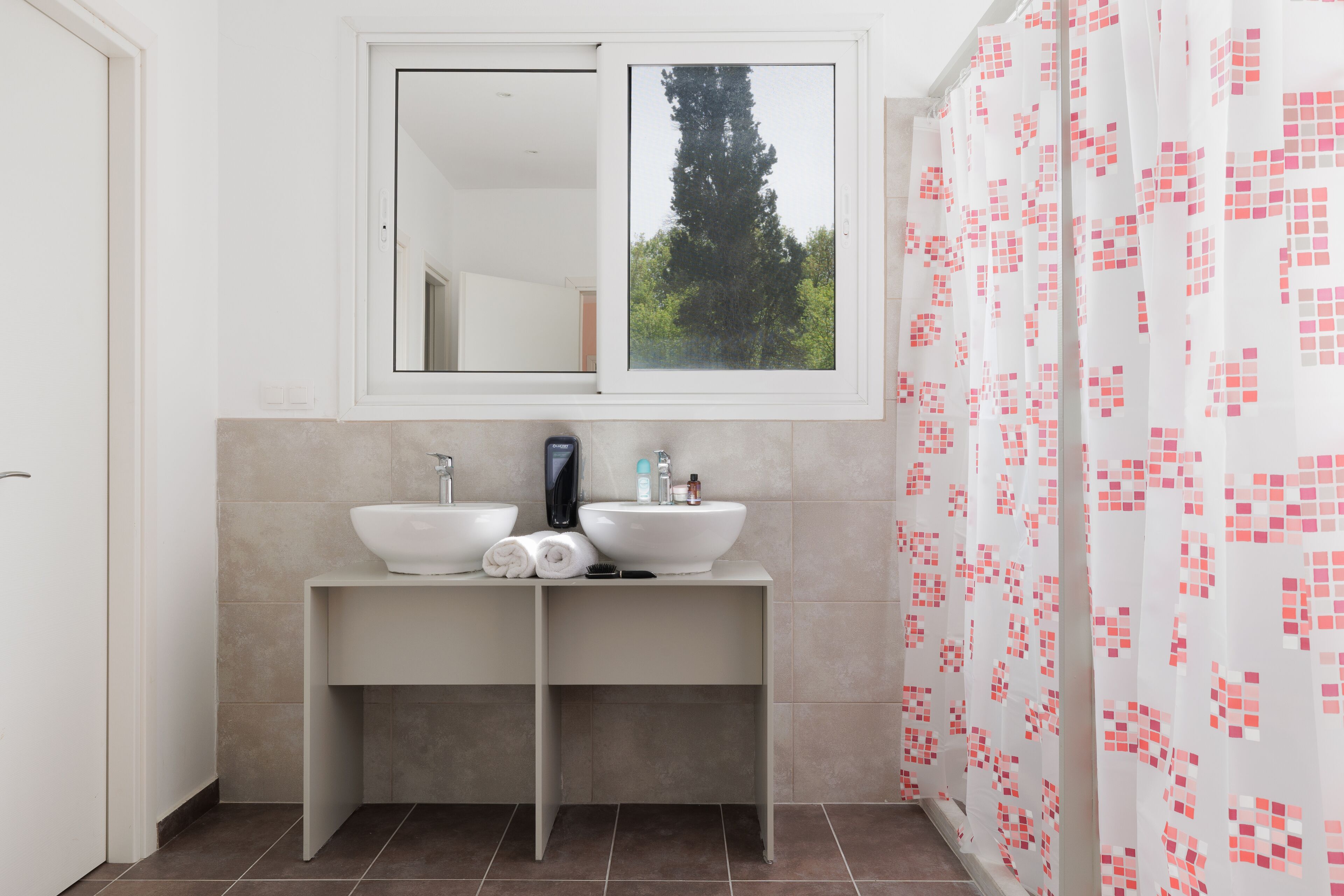 Une salle de bain moderne avec deux lavabos, un miroir et une fenêtre.