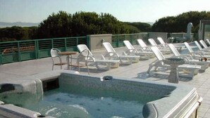 A rooftop pool area with lounge chairs and a hot tub. - Hotel Flora (Bibbona)