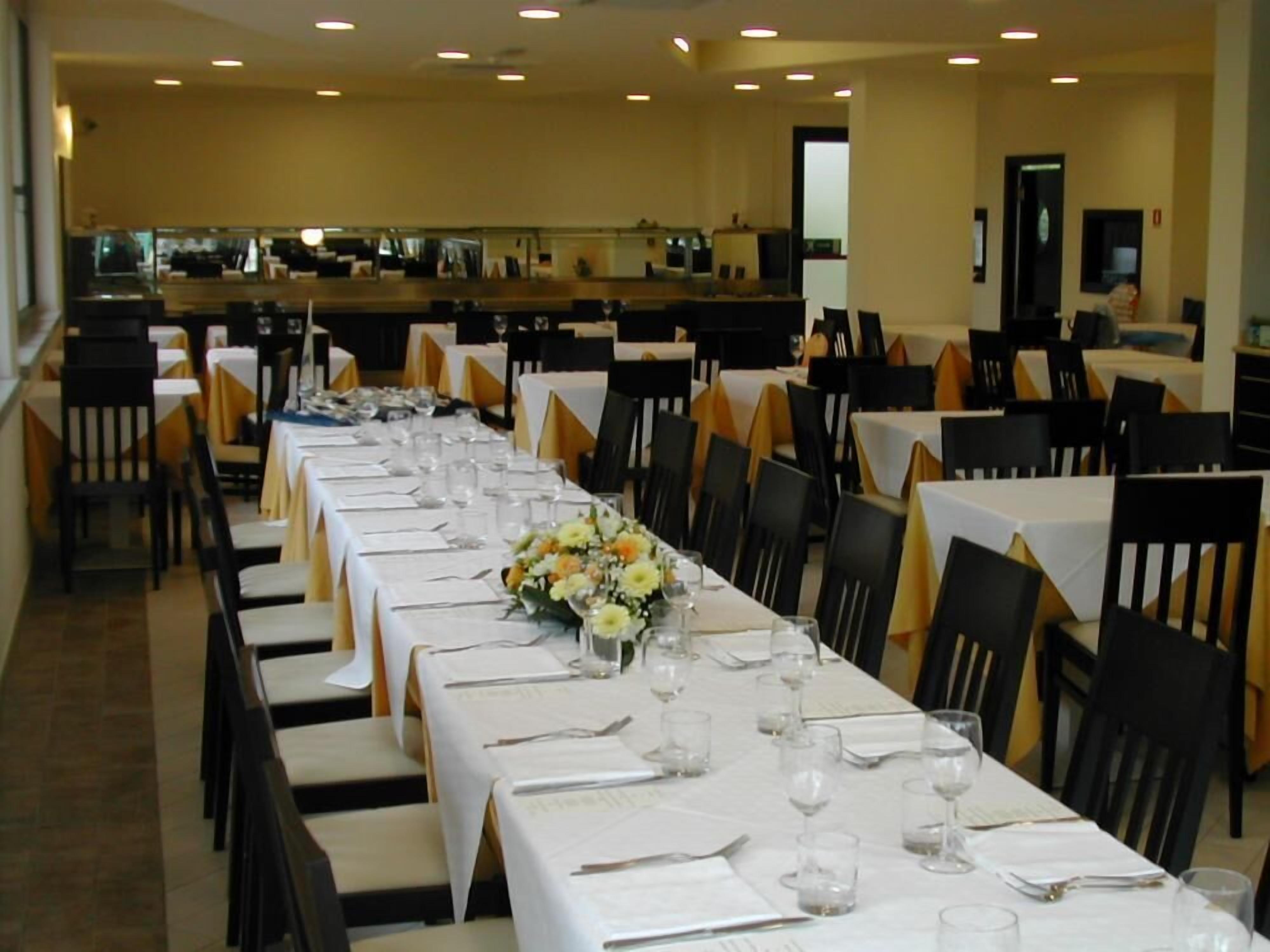 A banquet hall with multiple tables set for dining, each with white tablecloths and chairs.