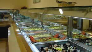 A buffet with various seafood options, including shrimp, mussels, and fish, displayed in glass containers. - Hotel Flora (Bibbona)