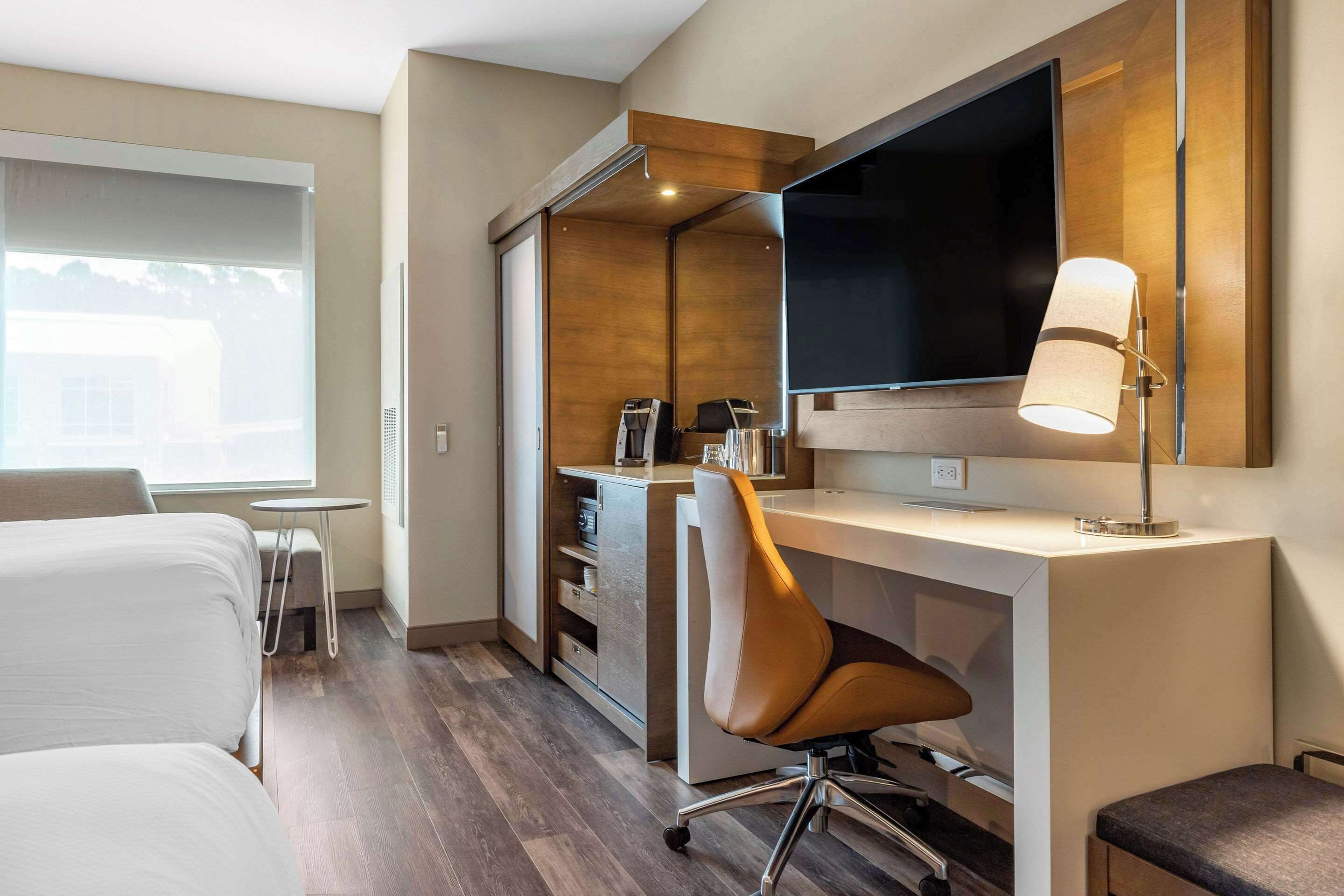 Een hotelkamer met een bed, een bureau, een stoel, een televisie en een lamp.