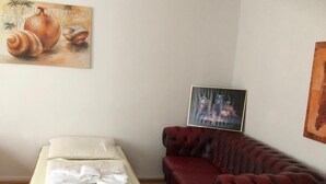 A room with a wooden bed, a red leather sofa, and two paintings on the walls. - City Hotel-Garni (Hannover)